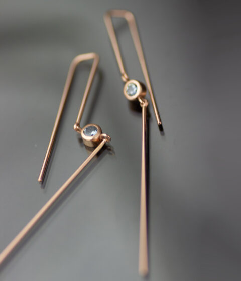 two earrings with montana sapphire gemstones and straight pieces of rose gold.