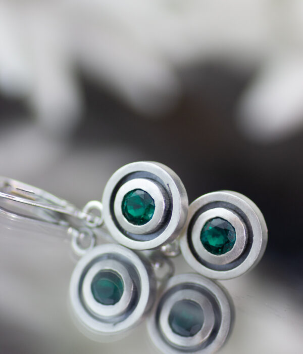 Sterling silver and emerald gemstone earrings with oxidized detailing in a double circular design.