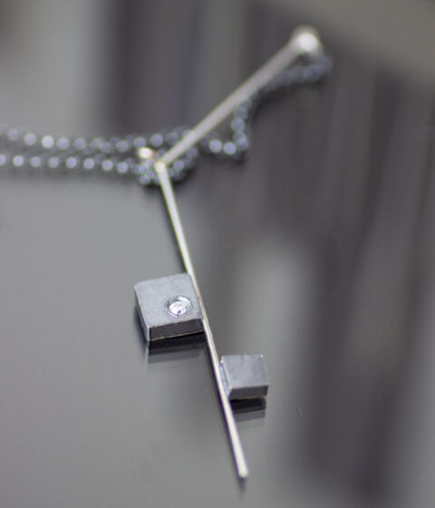 A square, geometric design necklace made with oxidized silver and platinum.